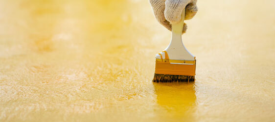Customize Your Garage Epoxy This image shows a man painting a floor using a paint brush.