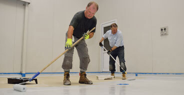 Professional Installation Lasts 10+ Years This image shows 2 men applying epoxy paint on a floor.