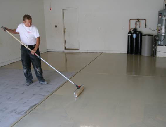 Metallic Epoxy Garage Floor This image shows a man painting a floor with a roller brush.