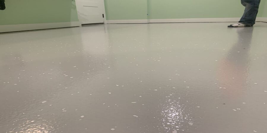 epoxy-floor-coating This image shows a man putting flakes on the floor.
